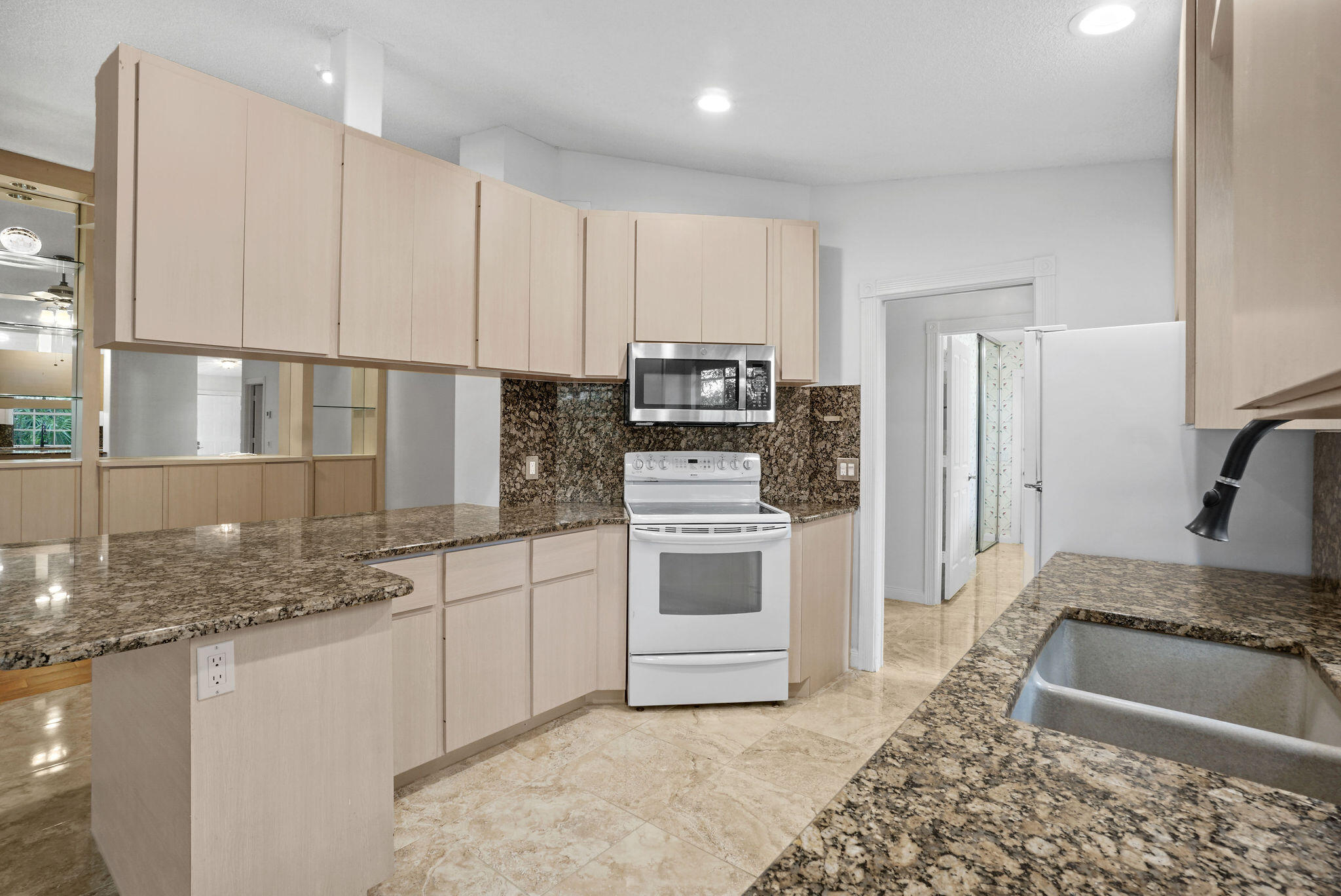 198 Brier Circle Jupiter, FL 33458 - Photo 16 of 38 a kitchen with kitchen island granite countertop a stove a sink and a refrigerator