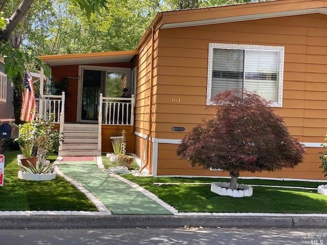 Front view mature landscaping with synthetic grass.