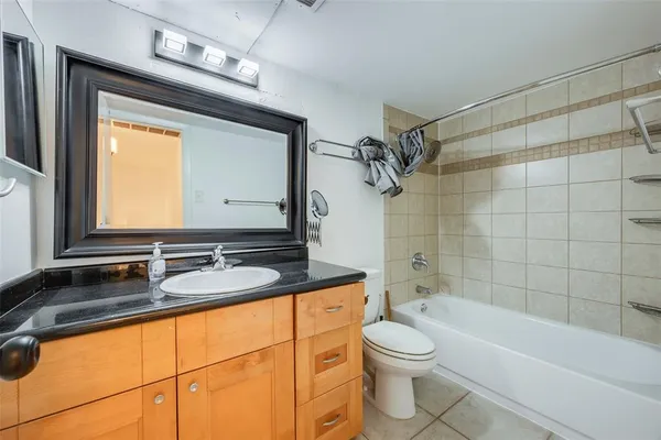 a bathroom with a granite countertop sink toilet a mirror and bathtub