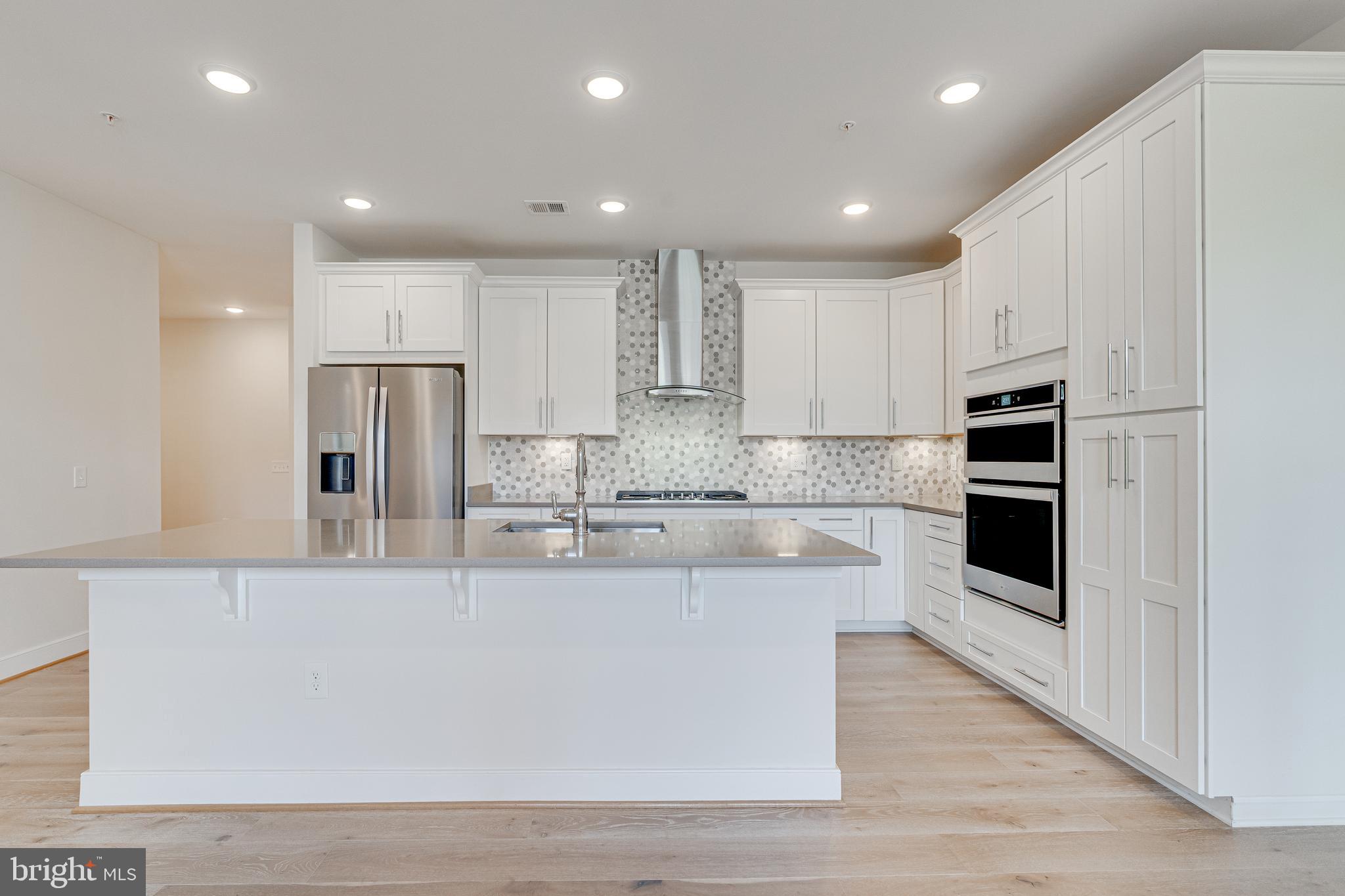 11200 Reston Station Boulevard, Unit 207 Reston, VA 20190 - Photo 5 of 40 a large kitchen with stainless steel appliances granite countertop a stove a sink and a refrigerator