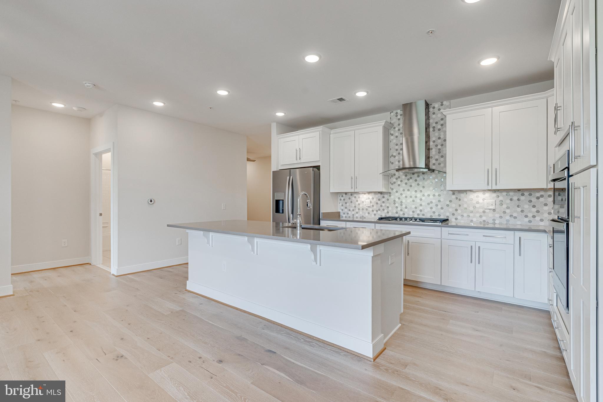 11200 Reston Station Boulevard, Unit 207 Reston, VA 20190 - Photo 6 of 40 a kitchen with stainless steel appliances granite countertop a white stove top oven and white cabinets