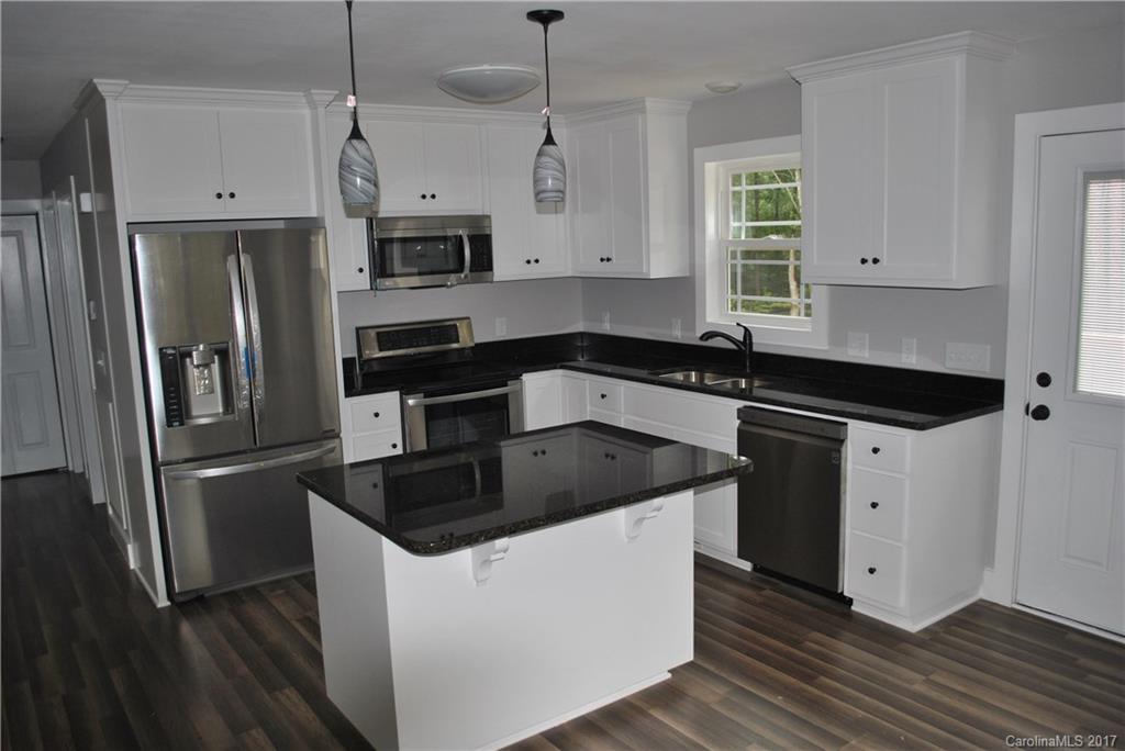 335 Creswell Road, Unit 1011 Mount Gilead, NC 27306 - Photo 7 of 18 a kitchen with stainless steel appliances a refrigerator a sink a stove a microwave and wooden floor