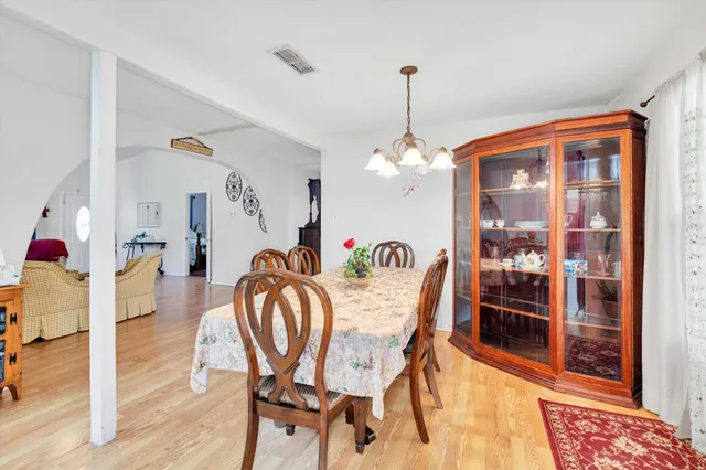 a dining room with furniture a chandelier and wooden floor