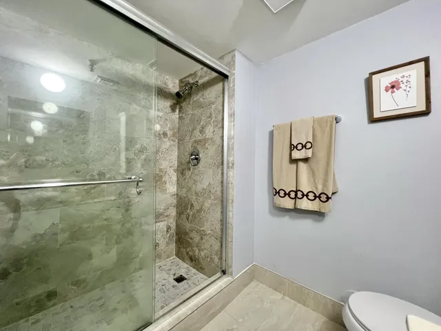 a bathroom with a granite countertop toilet sink and mirror