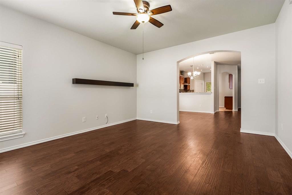 10969 Colonial Heights Lane Fort Worth, TX 76179 - Photo 16 of 34 an empty room with wooden floor chandelier fan and windows