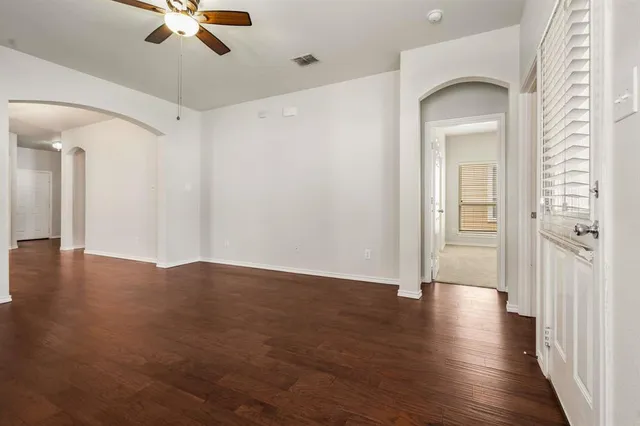 a view of a room with wooden floor fan and windows