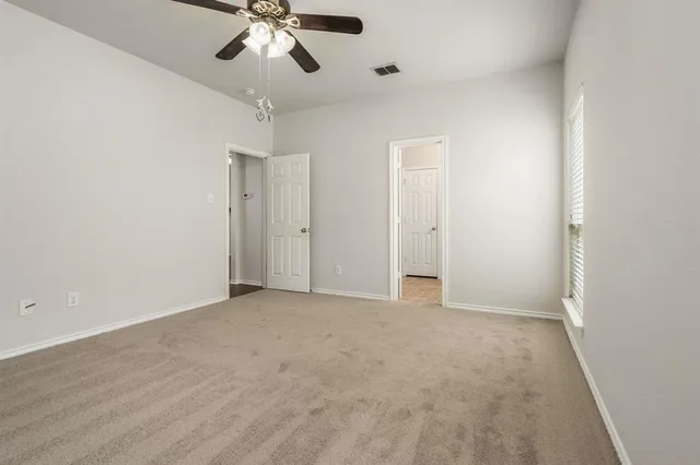 an empty room with chandelier fan and closet