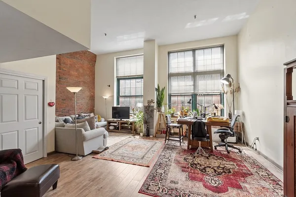 a living room with furniture large window and wooden floor