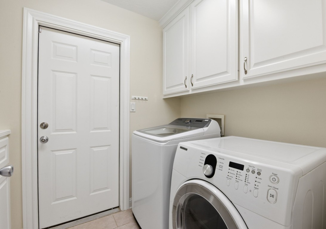 232 North Dixie Street Brenham, TX 77833 - Photo 21 of 41 This photo shows a clean, well-organized laundry room, upper cabinets for storage, and a door leading outside.