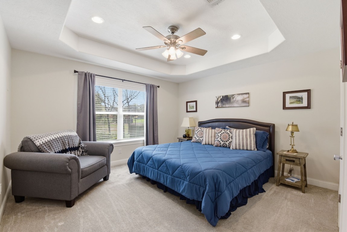 232 North Dixie Street Brenham, TX 77833 - Photo 22 of 41 This bedroom features a cozy atmosphere with soft carpeting. A ceiling fan and recessed lighting add brightness, while a window offers natural light and a view outside.
