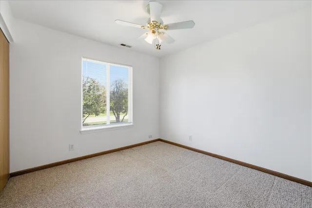 an empty room with a chandelier fan and windows