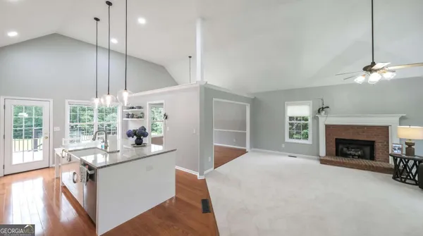 a kitchen with stainless steel appliances granite countertop a refrigerator a sink dishwasher a oven with white cabinets and wooden floor