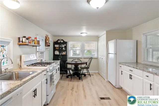 a kitchen with stainless steel appliances granite countertop a stove a refrigerator a sink dishwasher and white cabinets with wooden floor