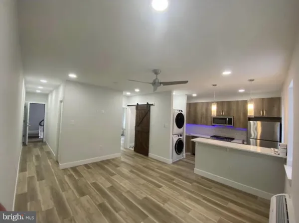 a room with stainless steel appliances kitchen island granite countertop a refrigerator and a sink