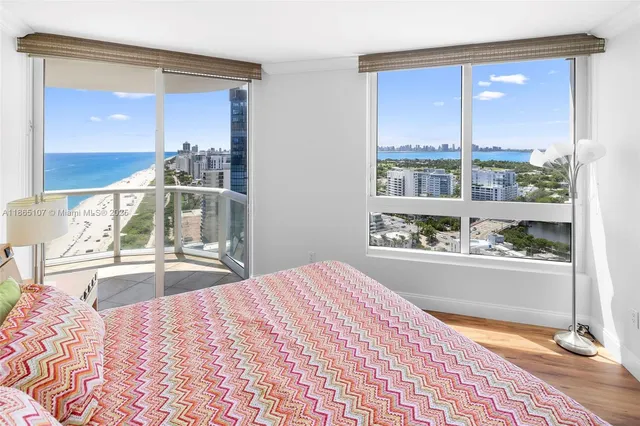 a view of a swimming pool with a lawn chairs under palm trees