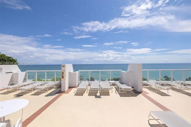 a view of a patio with table and chairs under an umbrella with a large window
