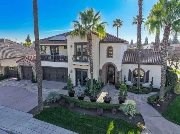 a front view of a house with a yard and palm trees
