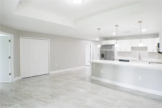 a large white kitchen with kitchen island a sink stainless steel appliances and cabinets