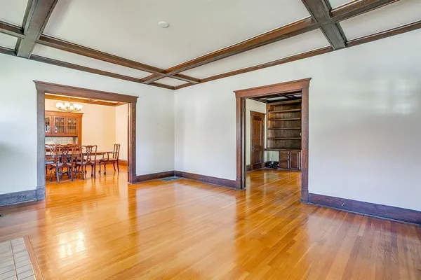 a view of empty room with wooden floor and a flat screen tv