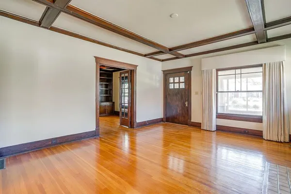 a view of an empty room with wooden floor and a window