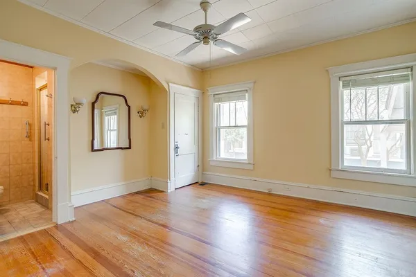 a view of empty room with wooden floor and fan
