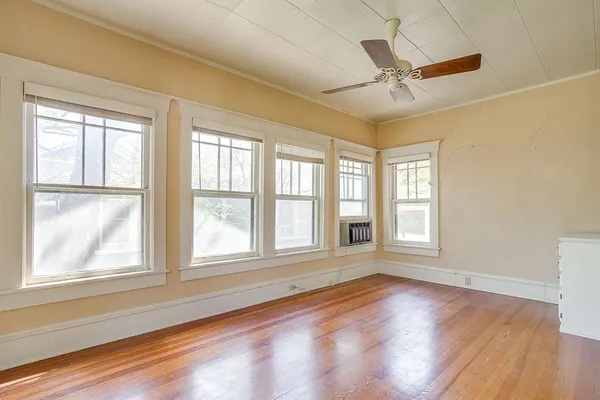 a view of an empty room with a window and wooden floor