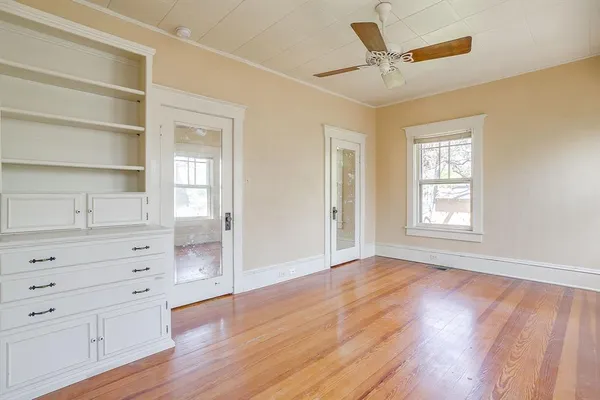 an empty room with wooden floor chandelier fan and windows