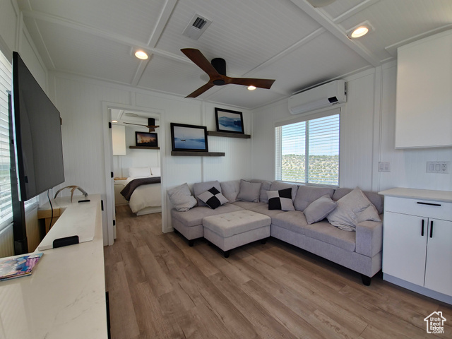 900 Altamont Road Evanston, WY 82930 - Photo 4 of 27 Living area with a wall mounted air conditioner, a ceiling fan, light wood finished floors, a decorative wall, and beamed ceiling