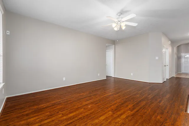 an empty room with chandelier fan and windows