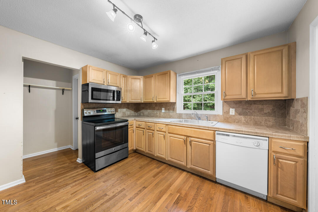 122 Stedwick Place Durham, NC 27712 - Photo 13 of 35 a kitchen with granite countertop a stove a sink and cabinets