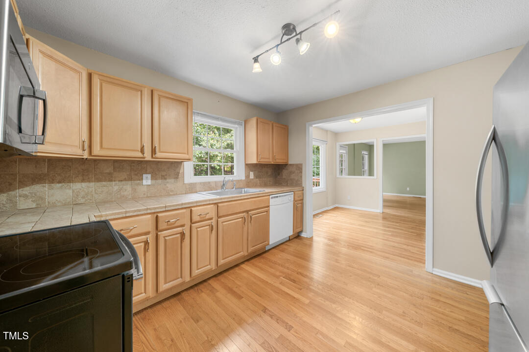 122 Stedwick Place Durham, NC 27712 - Photo 16 of 35 a kitchen with stainless steel appliances granite countertop a stove a sink dishwasher and a refrigerator with wooden floor