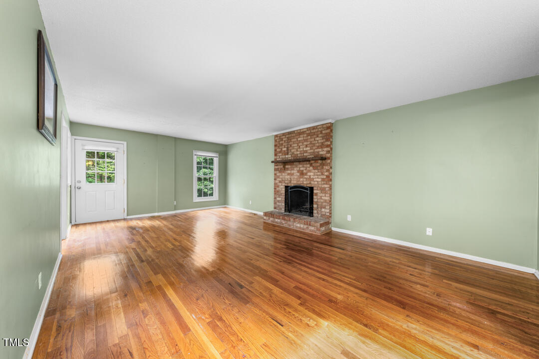 122 Stedwick Place Durham, NC 27712 - Photo 6 of 35 a view of empty room with wooden floor and fireplace