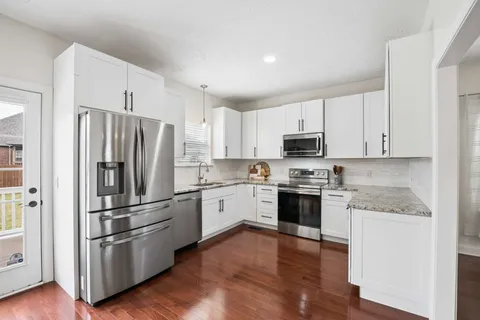 a kitchen with stainless steel appliances white cabinets and wooden floor