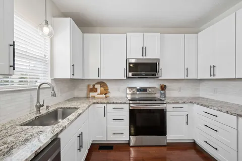 a kitchen with granite countertop white cabinets white stainless steel appliances and a sink