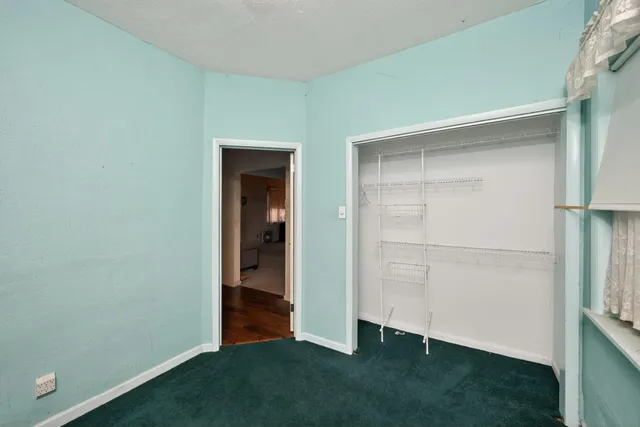 an empty room with wooden floor closet and windows
