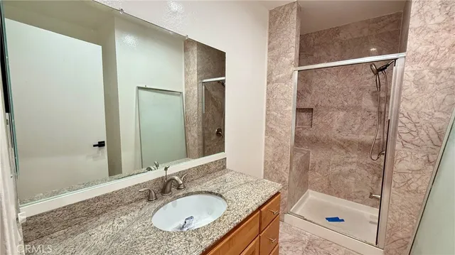 a bathroom with a granite countertop shower sink and mirror