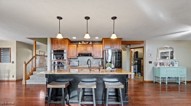 8995 Ridge Road Wooster, OH 44691 - Photo 22 of 50 Kitchen with appliances with stainless steel finishes, brown cabinetry, hanging light fixtures, decorative backsplash, and recessed lighting