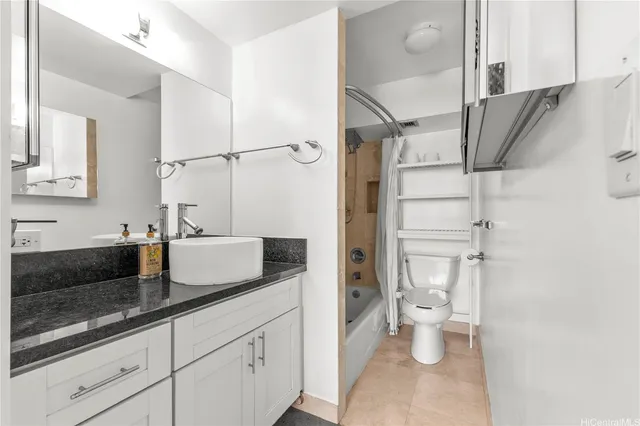 a bathroom with a granite countertop bathtub shower sink vanity and toilet