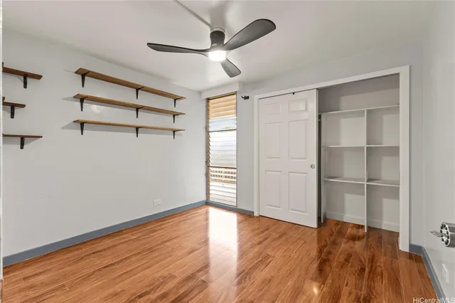 an empty room with wooden floor cabinet and windows