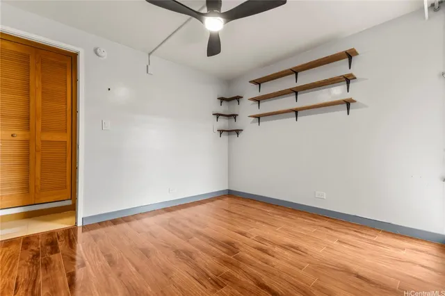 an empty room with wooden floor closet and windows