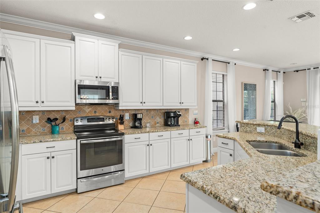 717 Desert Mountain Court Reunion, FL 34747 - Photo 16 of 62 a kitchen with stainless steel appliances granite countertop a sink stove and cabinets