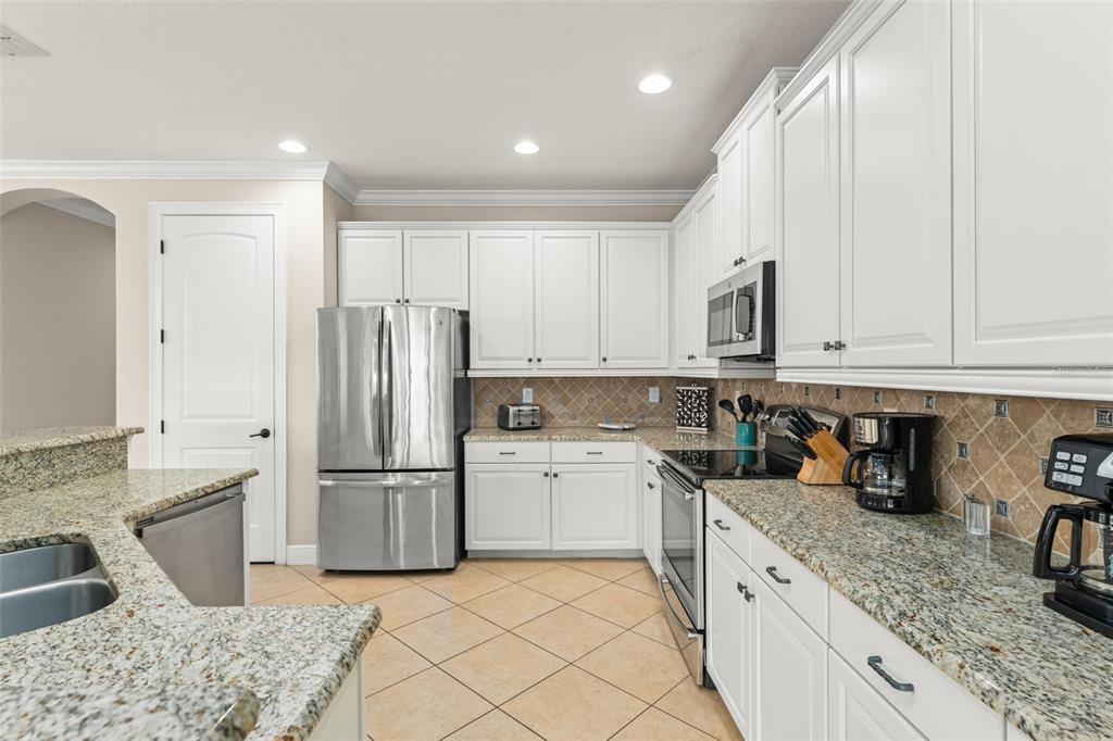717 Desert Mountain Court Reunion, FL 34747 - Photo 17 of 62 a kitchen with granite countertop a sink stainless steel appliances and white cabinets
