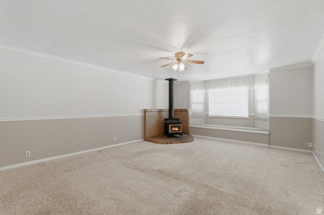 148 Tennyson Avenue Sandy, UT 84070 - Photo 16 of 55 Living area featuring a wood-burning stove with a brick surround, a bay window with integrated bench seating, neutral carpeting, and a ceiling fan
