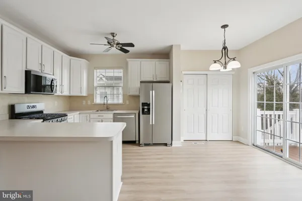 a kitchen with stainless steel appliances kitchen island granite countertop a refrigerator a sink dishwasher a stove and white cabinets with wooden floor