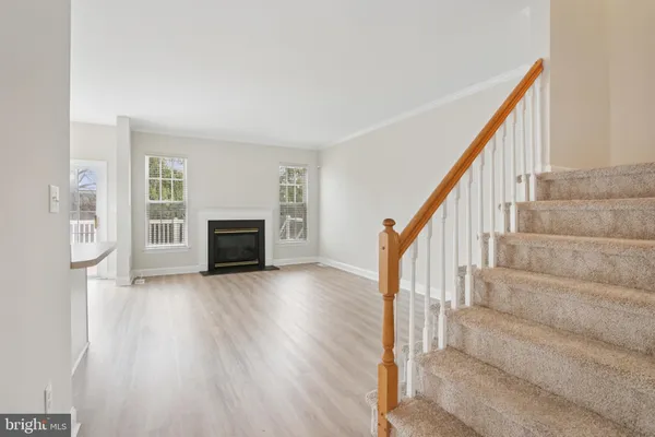 a view of an empty room with wooden floor and stairs