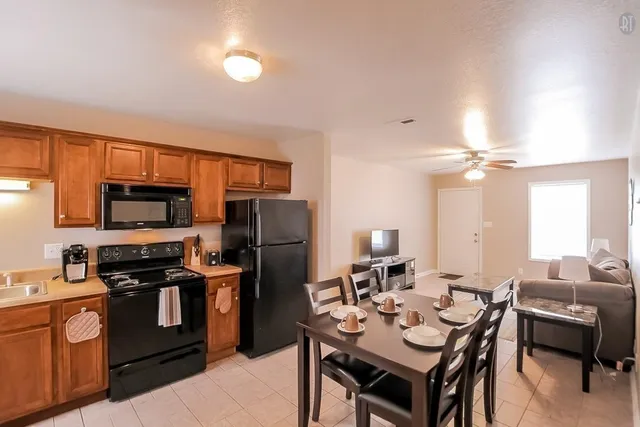 a kitchen with a refrigerator a stove a sink dishwasher a dining table and chairs with wooden floor