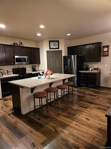 a kitchen with stainless steel appliances kitchen island granite countertop a refrigerator a stove a microwave and island with wooden floor