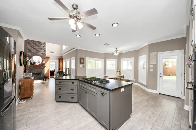 a kitchen with a stove a refrigerator a sink a dining table and chairs with wooden floor