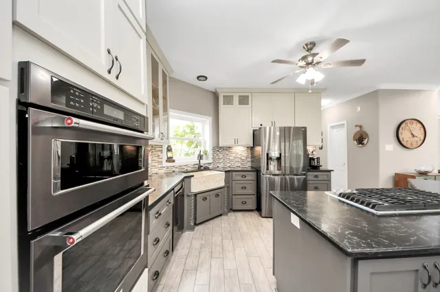 a kitchen with stainless steel appliances kitchen island granite countertop a stove and a sink