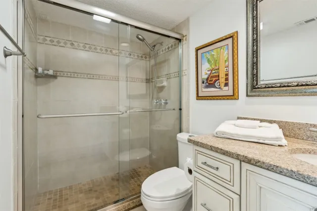 a bathroom with a granite countertop sink toilet a mirror and shower